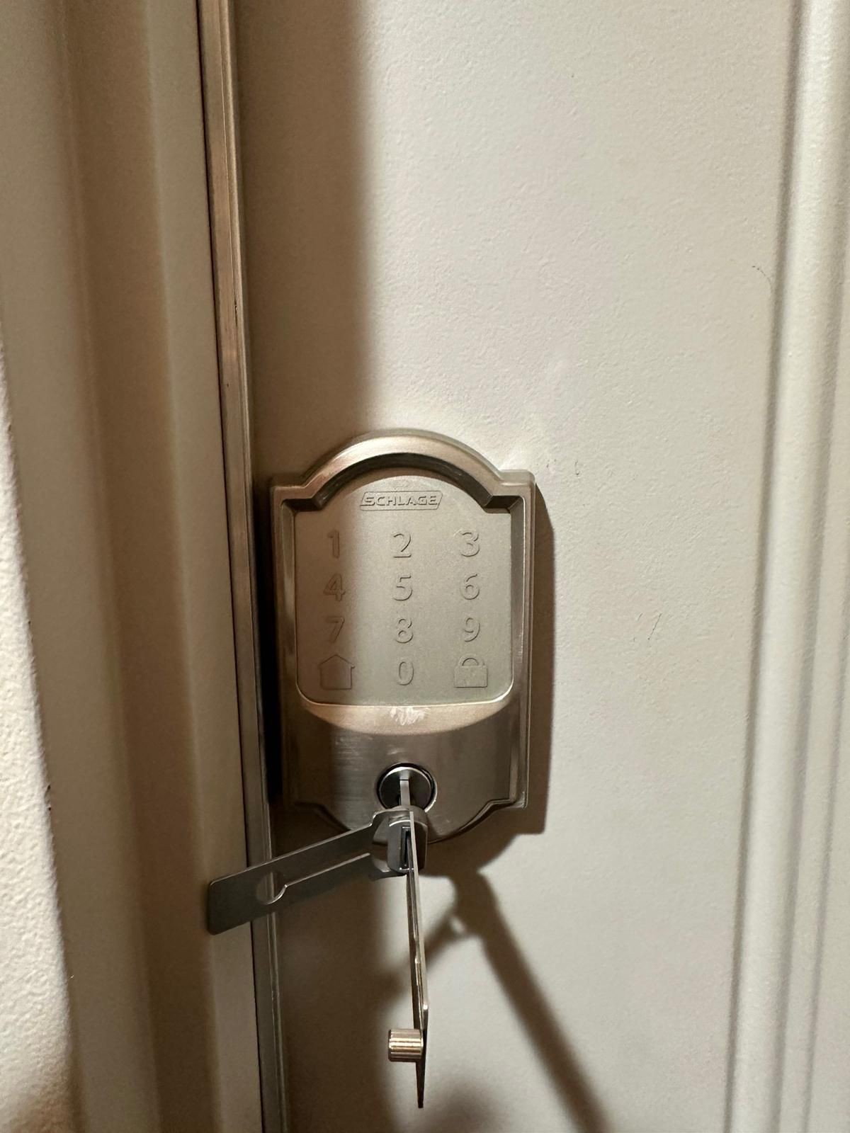 Close-up of a Schlage keypad door lock with a key inserted into the lower keyhole.